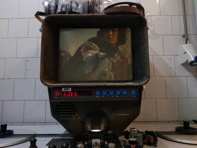 Colour photograph of a close up of a projector screen, showing a film of a woman with dark curly hair. Taken during the residency: 'alternative echelons' - by Amy Pickles and others, in collaboration with WORM Filmwerkplaats and UBIK, Autumn 2020.