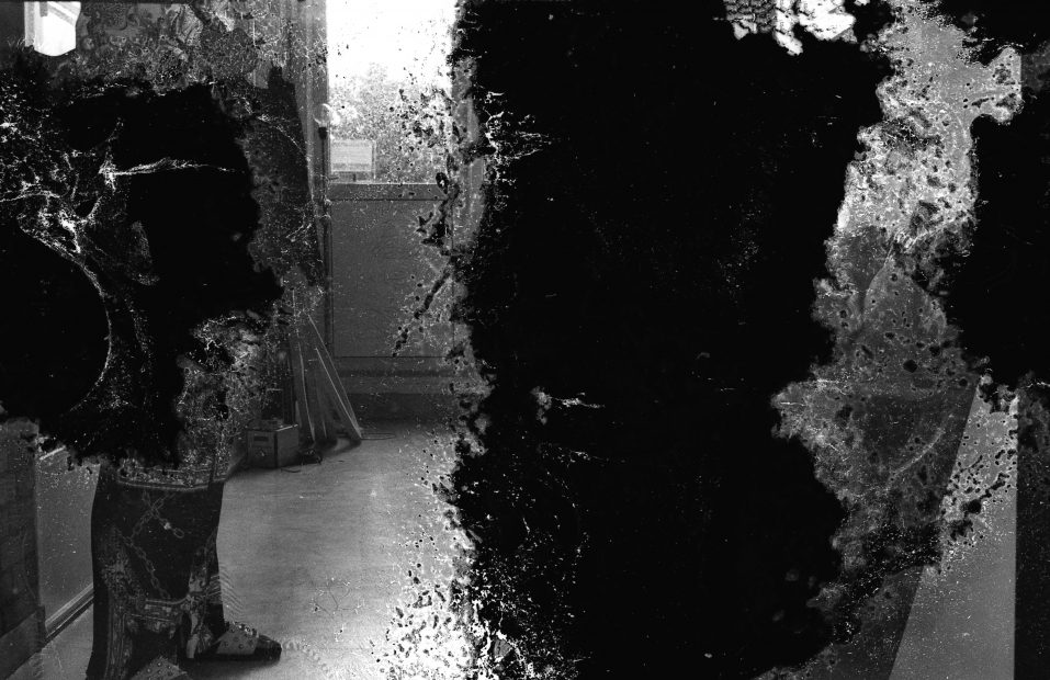 A treated black and white photograph, maybe deliberately treated to suggest a damaged print of an interior. A door in the background can be made out. Used in a WORM interview with the artist Susanne Khalil Yussef 2019.