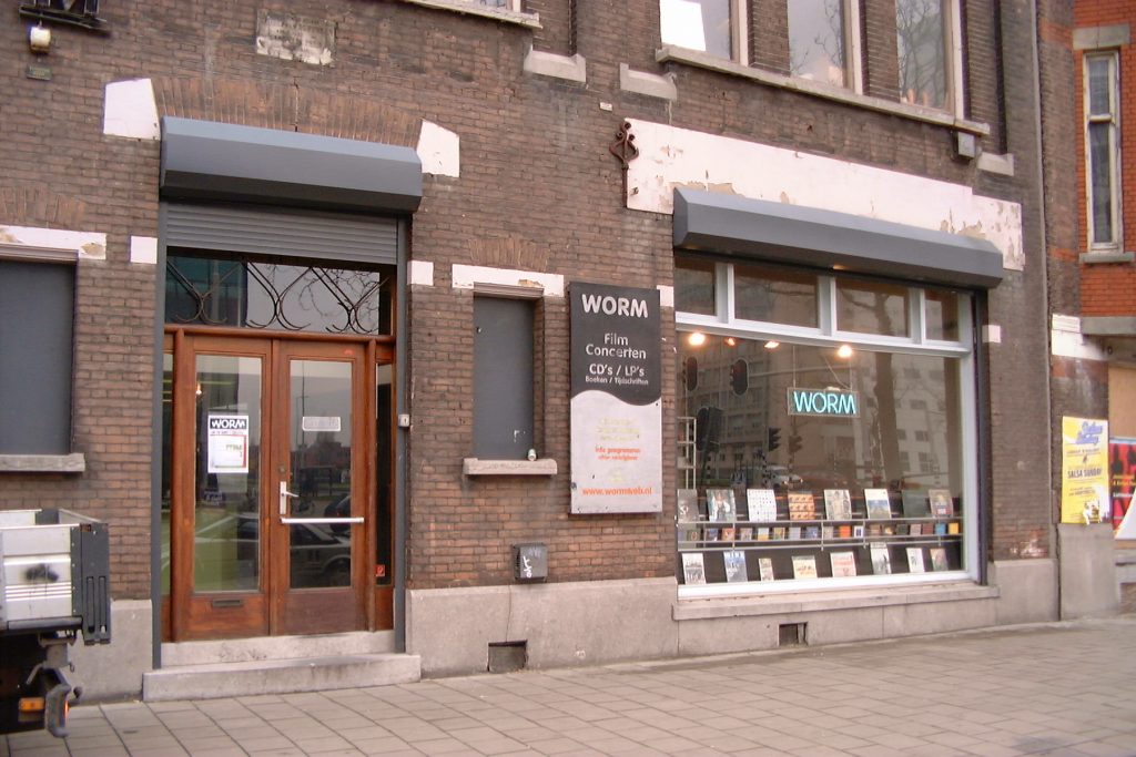A colour photograph of the exterior of WORM's first building on Rochussenstraat in Rotterdam. A brick building from the nineteenth-century with a large window.