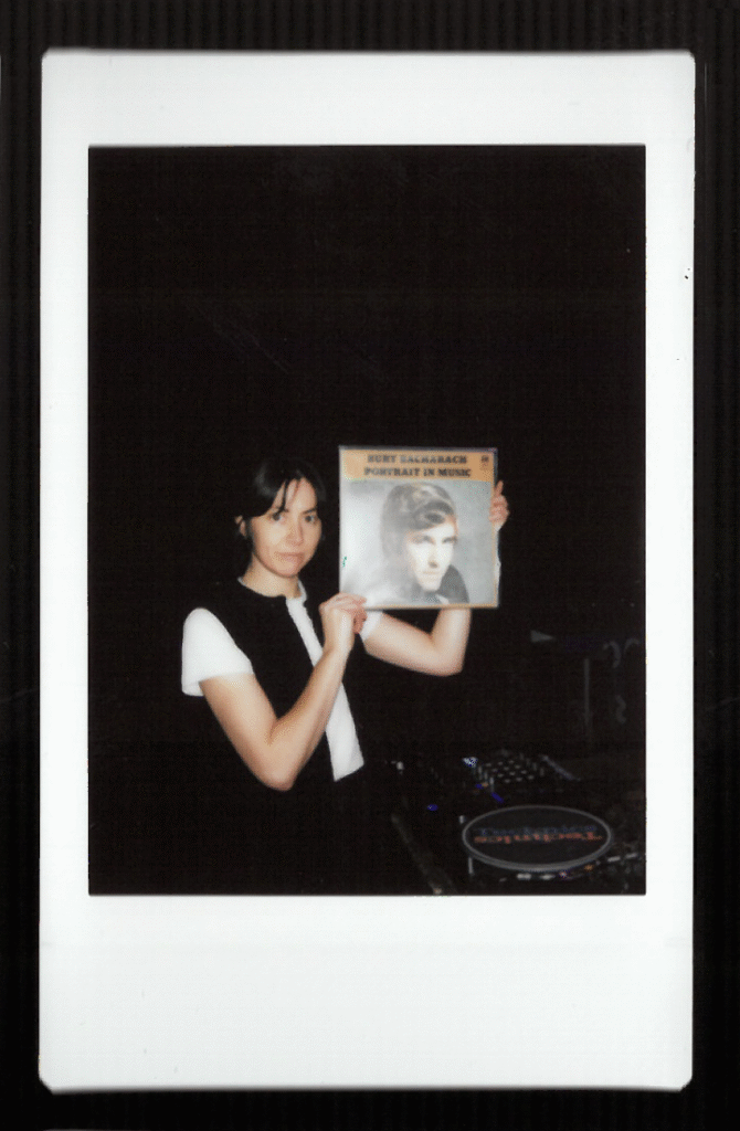 Colour photograph of the artist Ash Kilmartin holding up a Burt Bacharach record - dark background.