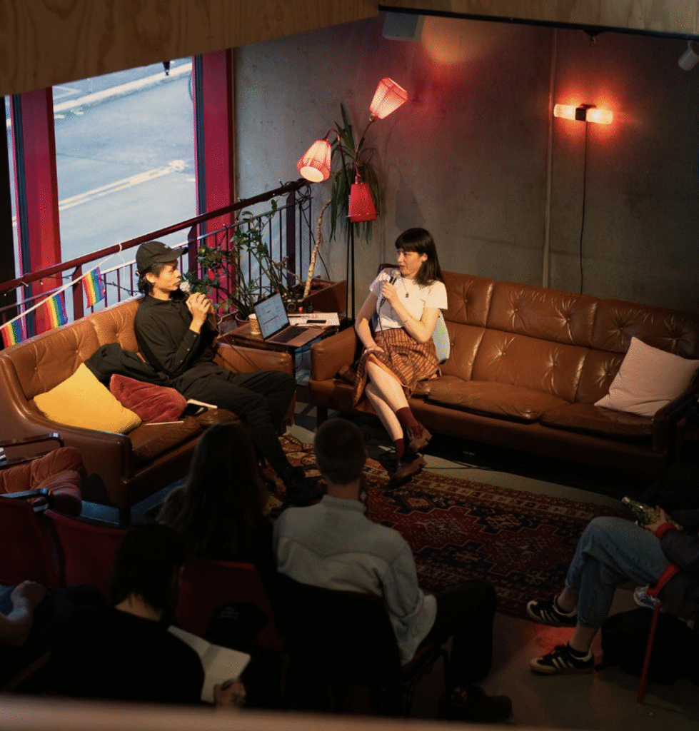 Photograph from an elevated position showing Ash Kilmartin - seated - interviewing another seated person
