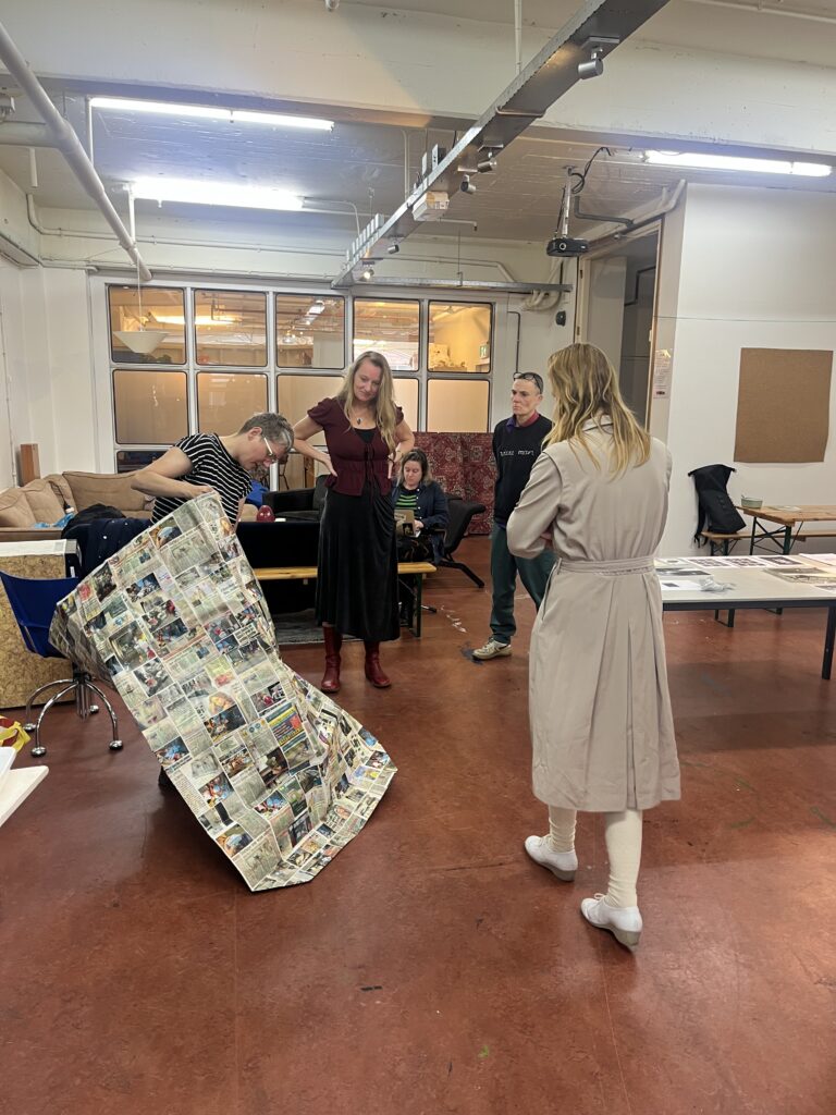 ieke Trinks presenting a Thonga, a Bengali word for a paper bag inspired on Indian newspaper bags, in the picture you see a human size paper bag including images of Trinks her performances with the bag.