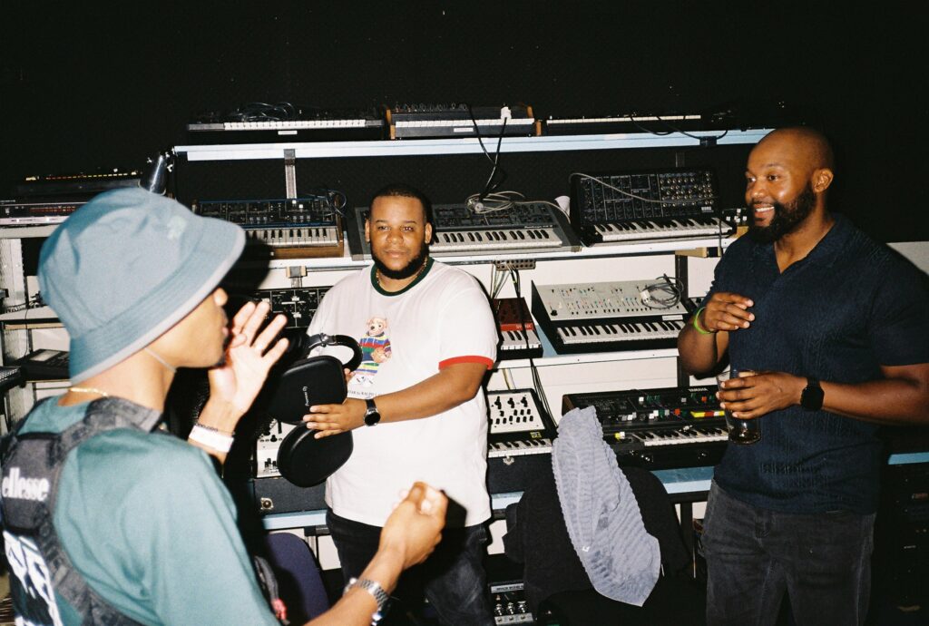 Colour photo by WORM club programmer Frederik Teixeira showing WORM Sound Studios and three men discussing something during the first edition of Roots and Riddims July 2025