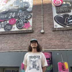 Colour ohoto of Matthias Carter standing under the murals on WORM's wall